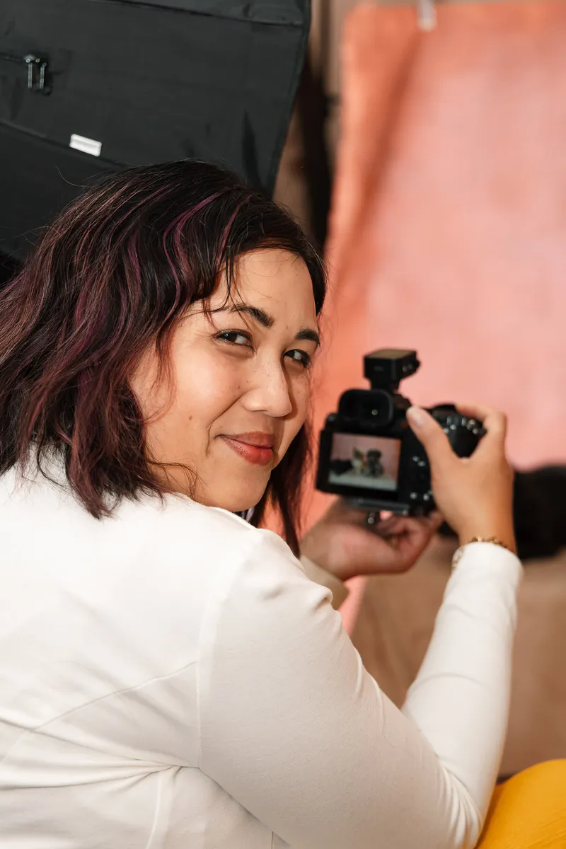 Pet photographer Ina J looking back over her shoulder while photographing two dogs on a studio backdrop