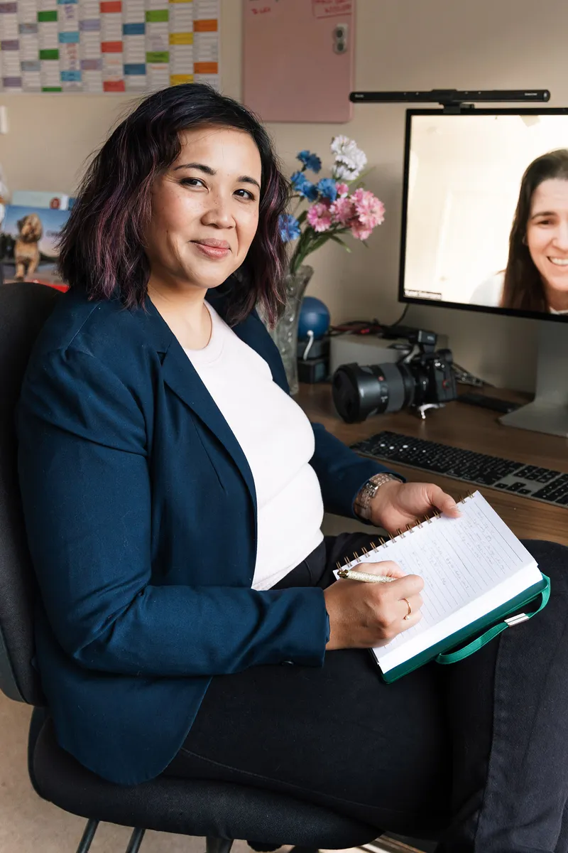 Pet photography business coach Ina J in a navy blazer at her desk, coaching a photographer on a video call